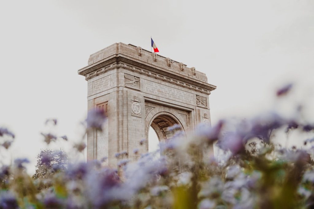 Beautiful view of Bucharests Triumphal Arch with vibrant flowers in the foreground.